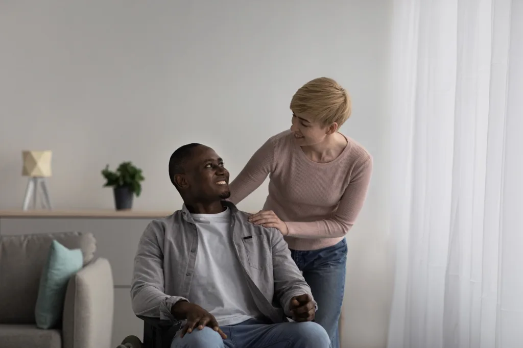 A woman is helping another man sit in his lap.