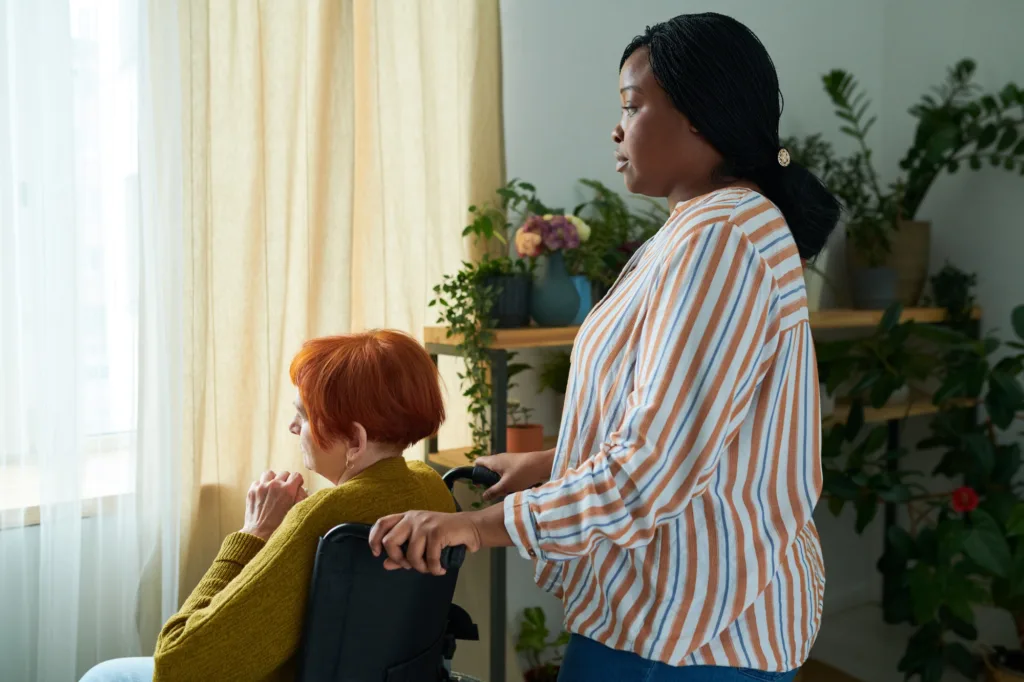 A woman standing next to another person in a chair.